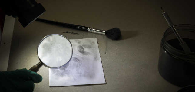 Magnifying glass and fingerprints on white paper